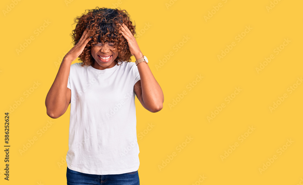 Young african american woman wearing casual white tshirt with hand on head for pain in head because stress. suffering migraine. Young african american woman wearing casual white tshirt with hand on head for pain in head because stress. suffering migraine.