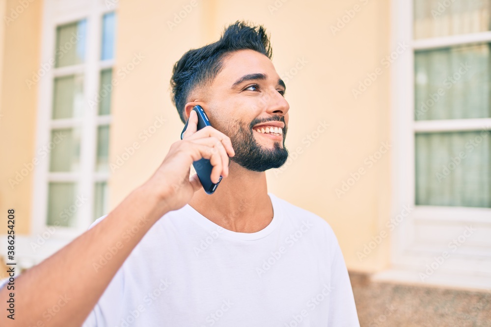 Young arab man with serious expression talking on the smartphone at the city. Young arab man with serious expression talking on the smartphone at the city.