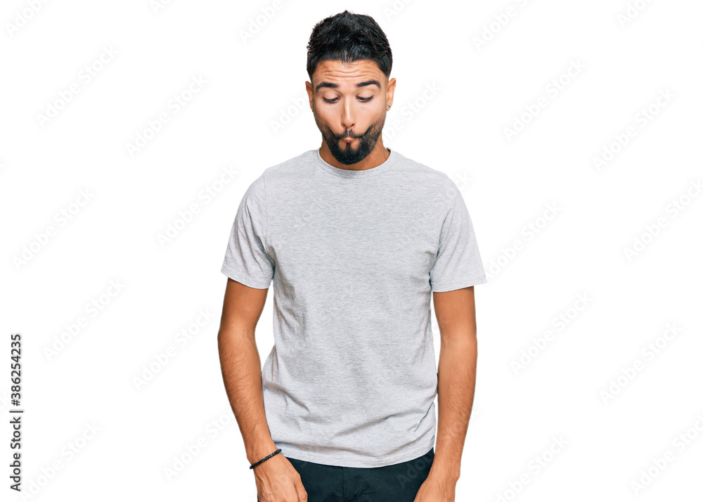 Young man with beard wearing casual grey tshirt making fish face with lips, crazy and comical gesture. funny expression. Young man with beard wearing casual grey tshirt making fish face with lips, crazy and comical gesture. funny expression.