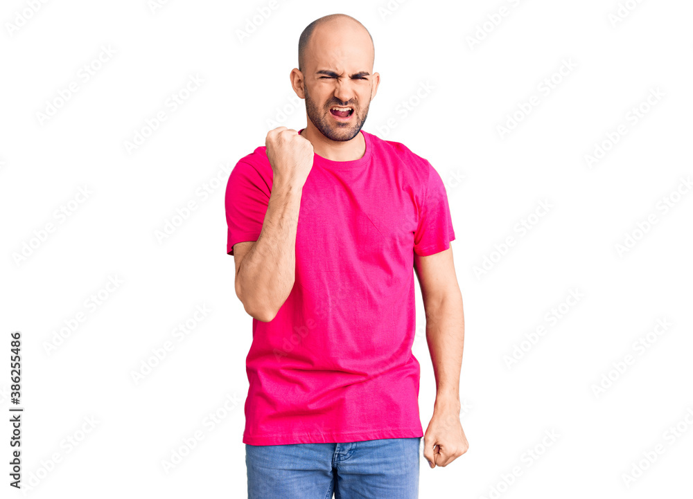 Fototapeta premium Young handsome man wearing casual t shirt angry and mad raising fist frustrated and furious while shouting with anger. rage and aggressive concept.