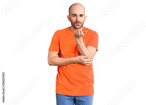 Young handsome man wering casual t shirt looking at the camera blowing a kiss with hand on air being lovely and sexy. love expression.