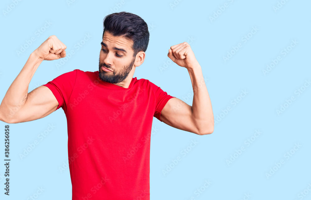 Young handsome man with beard wearing casual t-shirt showing arms muscles smiling proud. fitness concept. Young handsome man with beard wearing casual t-shirt showing arms muscles smiling proud. fitness concept.