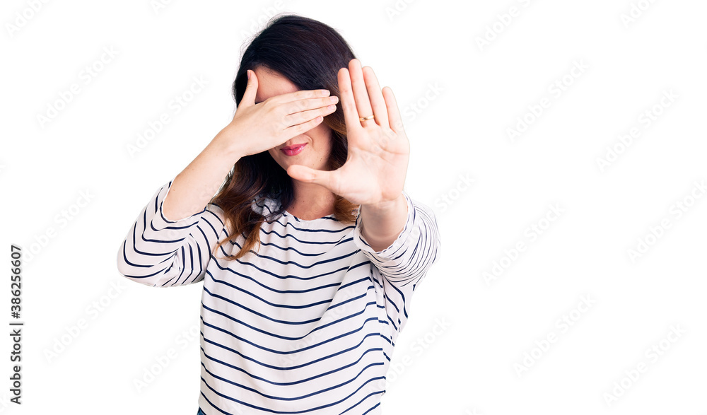 Beautiful young brunette woman wearing casual clothes and glasses covering eyes with hands and doing stop gesture with sad and fear expression. embarrassed and negative concept. Beautiful young brunette woman wearing casual clothes and glasses covering eyes with hands and doing stop gesture with sad and fear expression. embarrassed and negative concept.