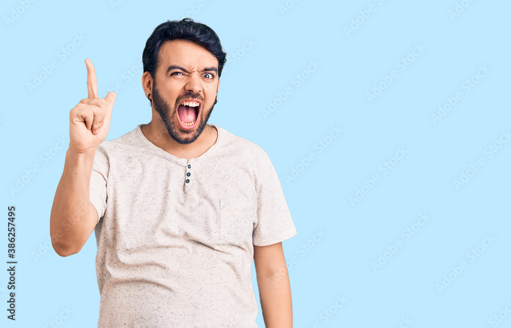 Young hispanic man wearing casual clothes pointing finger up with successful idea. exited and happy. number one. Young hispanic man wearing casual clothes pointing finger up with successful idea. exited and happy. number one.