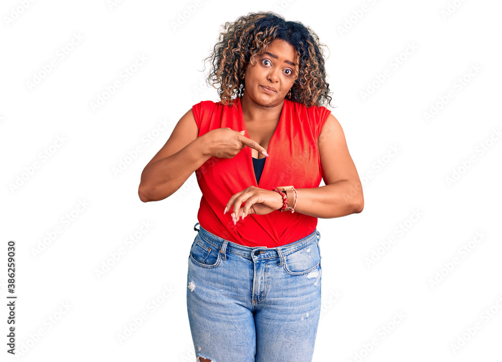 Young african american plus size woman wearing casual style with sleeveless shirt in hurry pointing to watch time, impatience, upset and angry for deadline delay