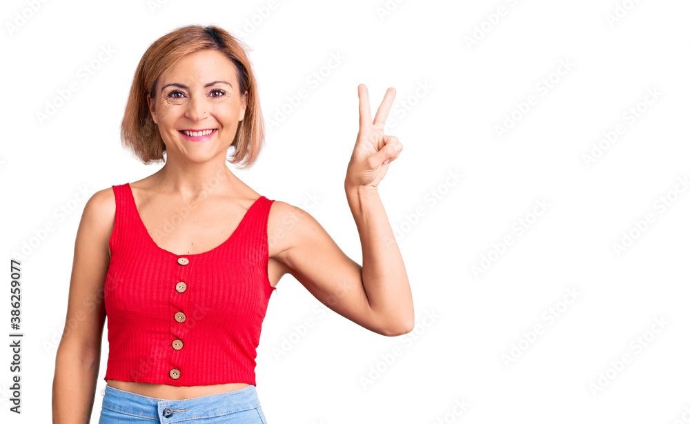 Young blonde woman wearing casual clothes smiling with happy face winking at the camera doing victory sign. number two. Young blonde woman wearing casual clothes smiling with happy face winking at the camera doing victory sign. number two.