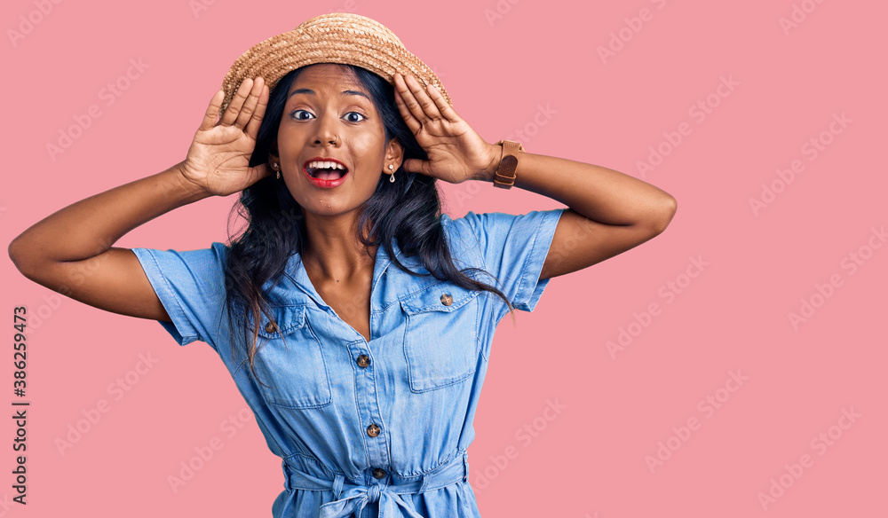 Young indian girl wearing summer hat smiling cheerful playing peek a boo with hands showing face. surprised and exited Young indian girl wearing summer hat smiling cheerful playing peek a boo with hands showing face. surprised and exited
