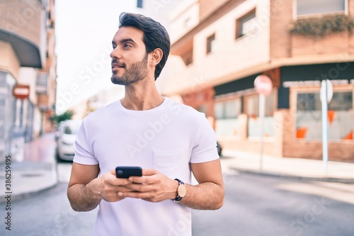 Young hispanic man smiling happy using smartphone at city. © Krakenimages.com