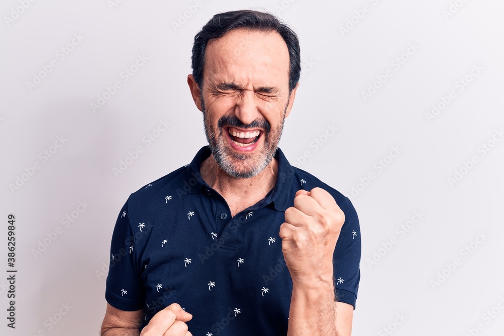 Naklejka premium Middle age handsome man wearing casual polo standing over isolated white background celebrating surprised and amazed for success with arms raised and eyes closed