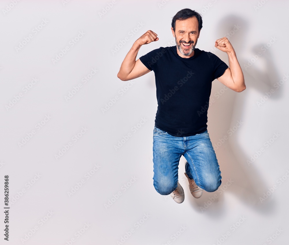 Middle age handsome man wearing casual clothes smiling happy. Jumping with smile on face doing winner gesture with fists up over isolated white background Middle age handsome man wearing casual clothes smiling happy. Jumping with smile on face doing winner gesture with fists up over isolated white background