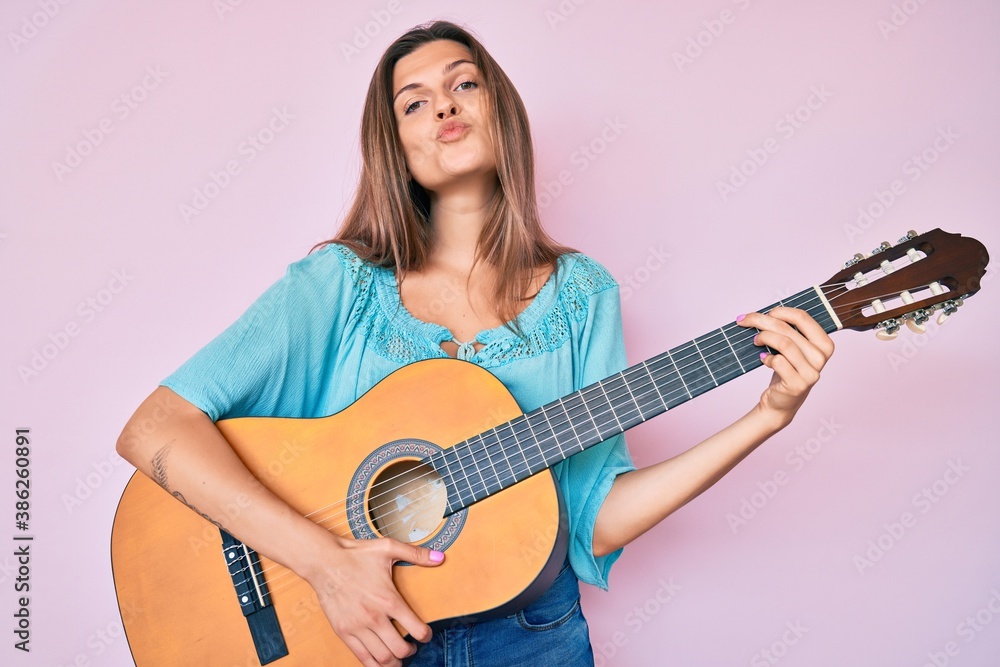 Beautiful caucasian woman playing classical guitar looking at the camera blowing a kiss being lovely and sexy. love expression. Beautiful caucasian woman playing classical guitar looking at the camera blowing a kiss being lovely and sexy. love expression.