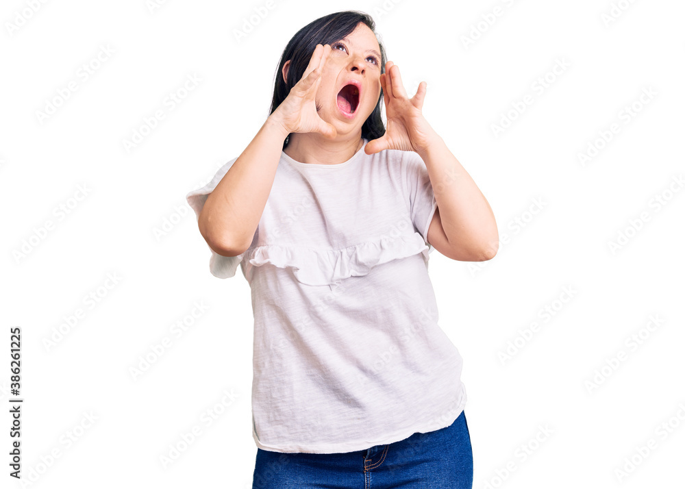 Brunette woman with down syndrome wearing casual white tshirt shouting angry out loud with hands over mouth Brunette woman with down syndrome wearing casual white tshirt shouting angry out loud with hands over mouth