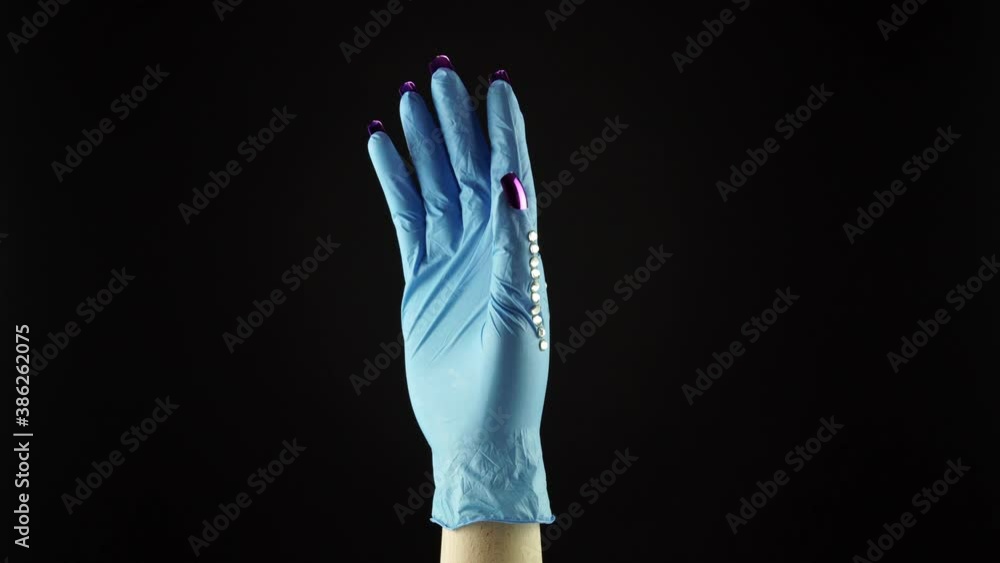 Woman wrist hand in the blue medical decorated glove PPE on black background. Female palm in disposable surgical protective glove. Concept of COVID 19 coronavirus pandemic front liners and nurse. Woman wrist hand in the blue medical decorated glove PPE on black background. Female palm in disposable surgical protective glove. Concept of COVID 19 coronavirus pandemic front liners and nurse.
