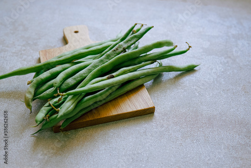 green beans are placed on a wooden cutting board with copyspace