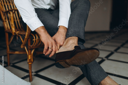 Groom is wearing shoes indoors. Male portrait of handsome guy.