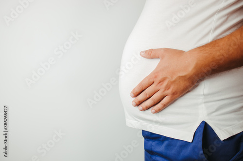 Overweight man holding big belly, copy space