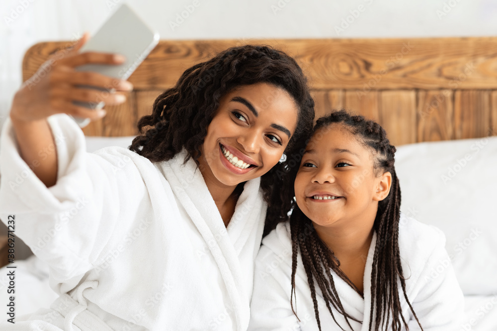 Cheerful African Mother And Daughter In Bathrobes Taking Selfie On Smartphone Cheerful African Mother And Daughter In Bathrobes Taking Selfie On Smartphone