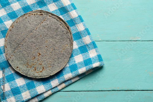 Mexican blue corn tortilla on turquoise background