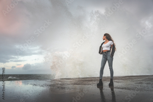 Young woman attending how the waves hit the rocks.