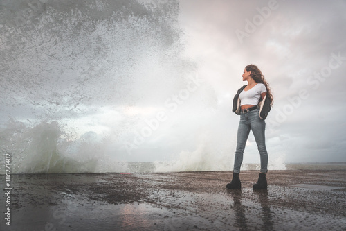 Young woman attending how the waves hit the rocks.