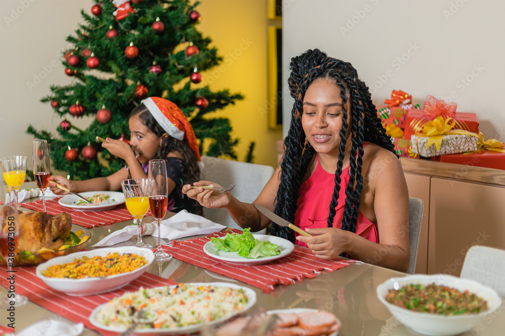 Summer Christmas dinner in Brazil. Real Brazilian family having fun at the Latin American Christmas party. latin woman with twisted hair having dinner with sister