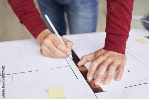 Closeup background of unrecognizable architect drawing blueprints while leaning on desk at workplace, copy space