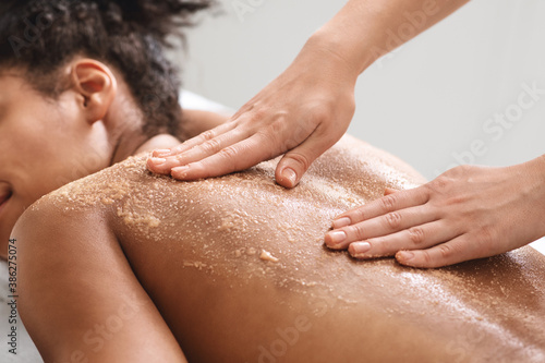 African american lady having skin scrubbing procedure at spa salon
