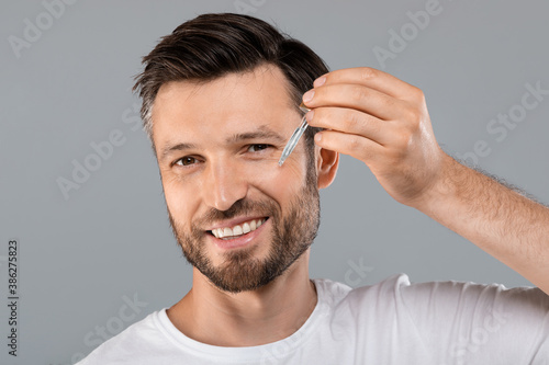 Middle-aged handsome man applying anti-aging face serum