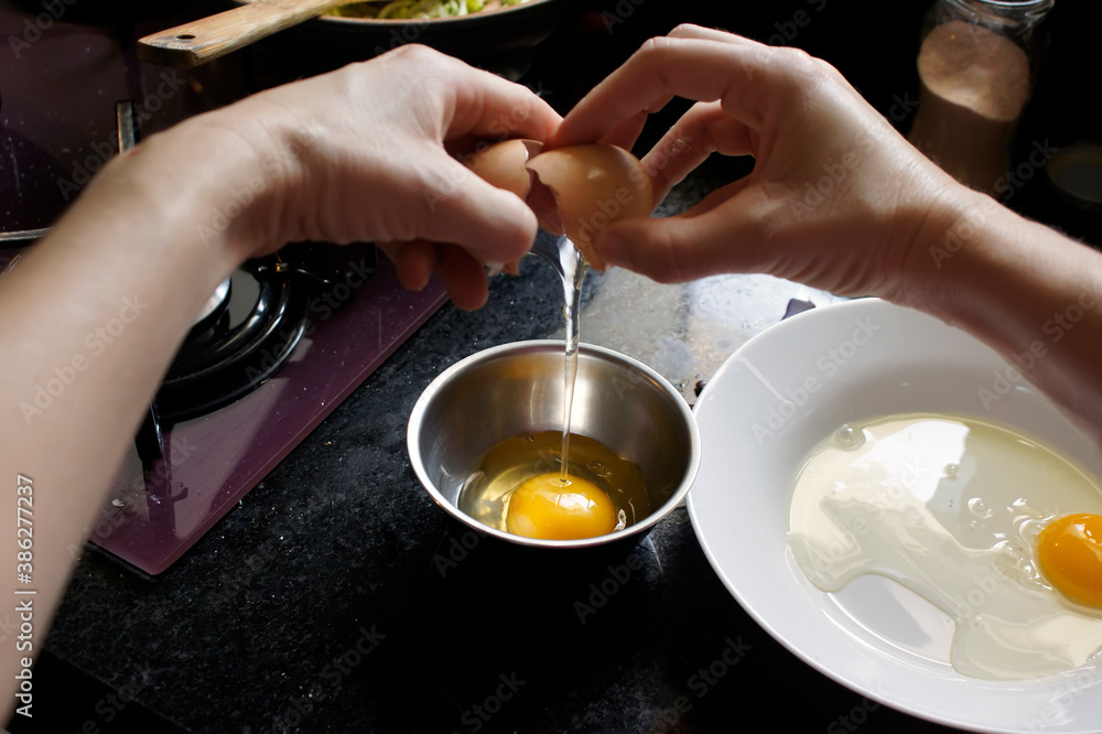 Woman breaking eggs to make omelet at home. Focus on the egg. Point of view Woman breaking eggs to make omelet at home. Focus on the egg. Point of view