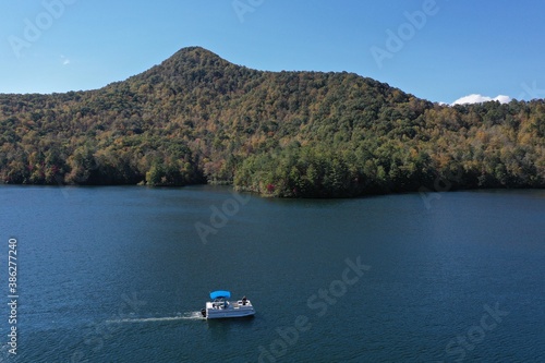 Aerial image of Funnel Top mountain and Lake Santeetlah, North Carolina in autumn color with pontoon boat in foreground.