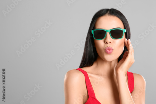 Beautiful woman wearing sunglasses on grey background. Space for text