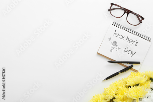 Beautiful flowers, glasses and notebook with words TEACHER'S DAY on white background, flat lay. Space for text