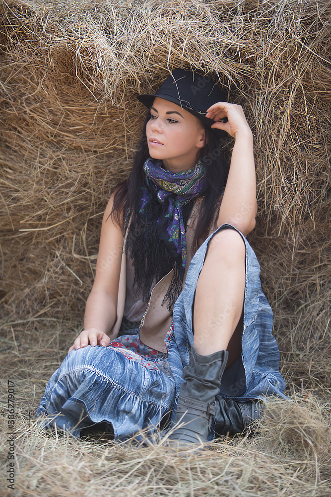 Beautiful young woman on the hay in the style of boho