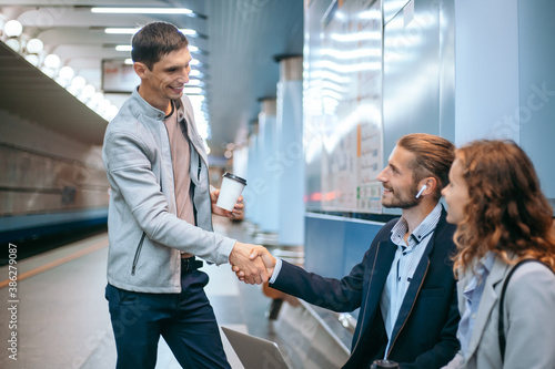business colleagues shaking hands on the subway platform.