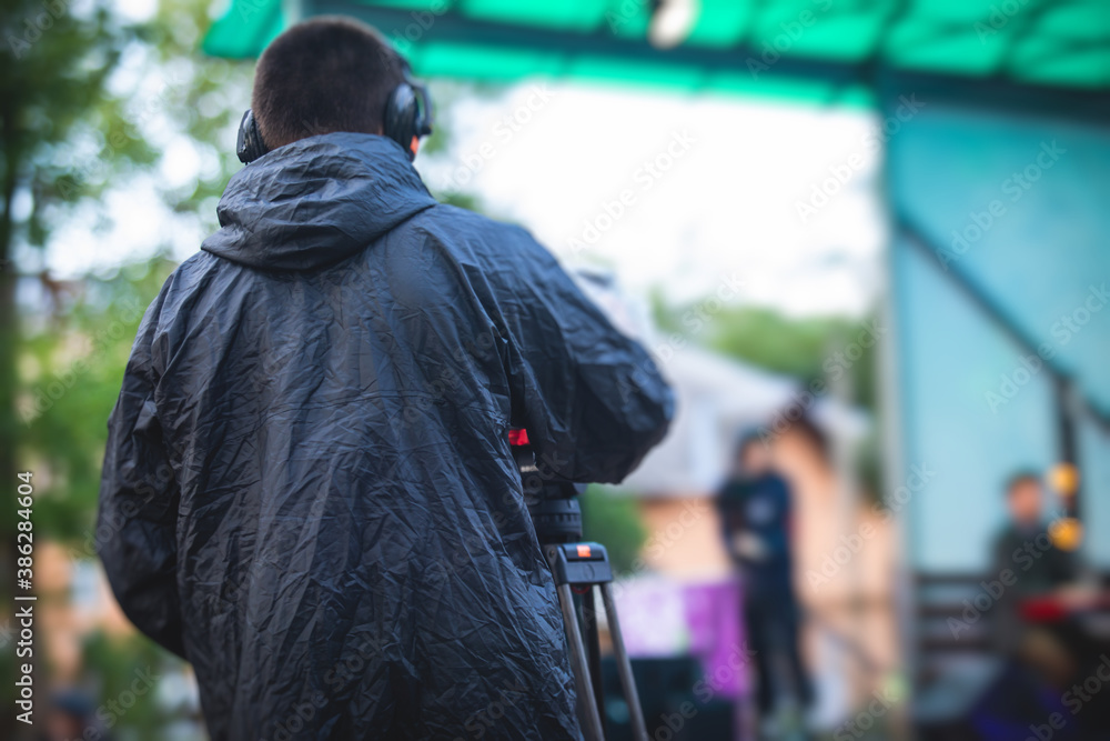 View of a camera man operator working during tv reportage, online broadcasting of concert, professional videographer with camera filming live event View of a camera man operator working during tv reportage, online broadcasting of concert, professional videographer with camera filming live event