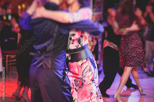 Couples dancing traditional latin argentinian dance milonga in the ballroom, tango salsa bachata lesson in the red lights, dance festival