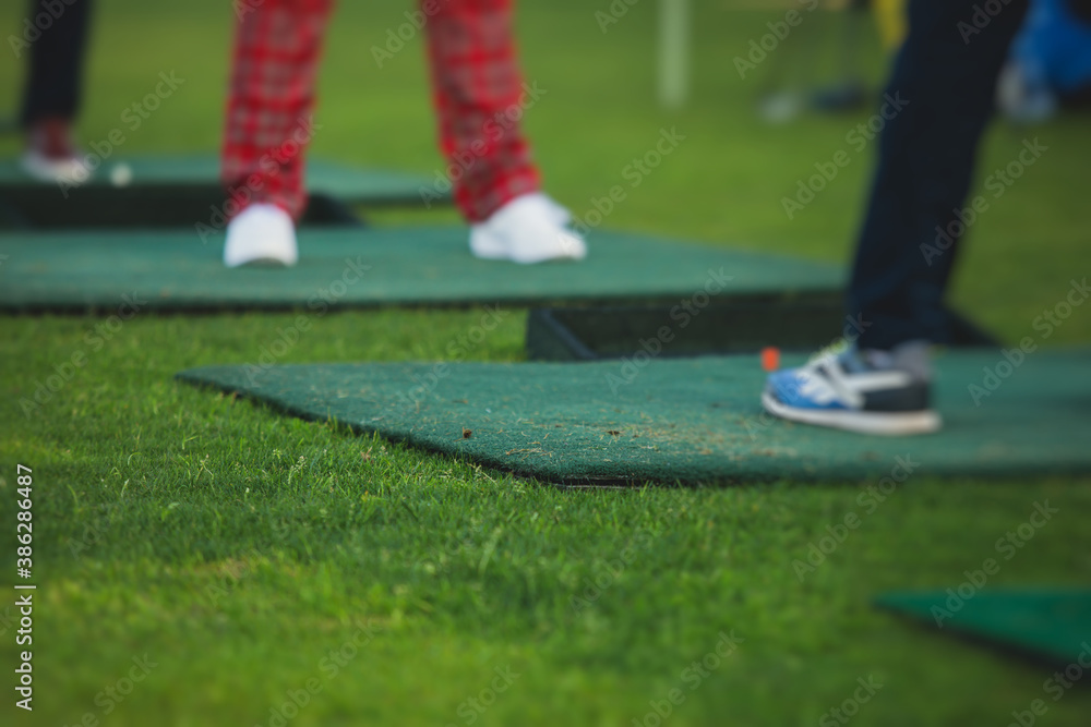 Obraz premium Group of golfers practicing and training golf swing on driving range practice, men playing on golf course, golf ball at golfing complex club resort