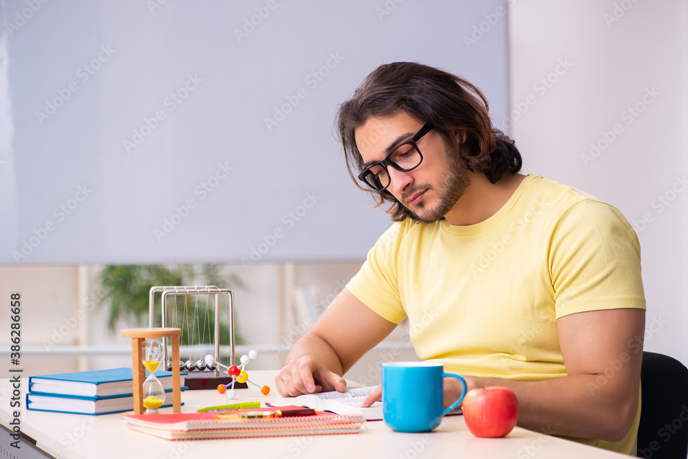 Young male student physicist preparing for exams in the classroo Young male student physicist preparing for exams in the classroo