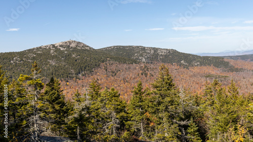 The rocky peaks of Cardigan Mountain and Firescrew Mountain rise above a forest of autumn foliage