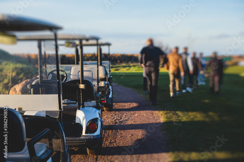 Golf electric cars riding on a golf course in the sunny day, golf carts drive with golfers in resort club