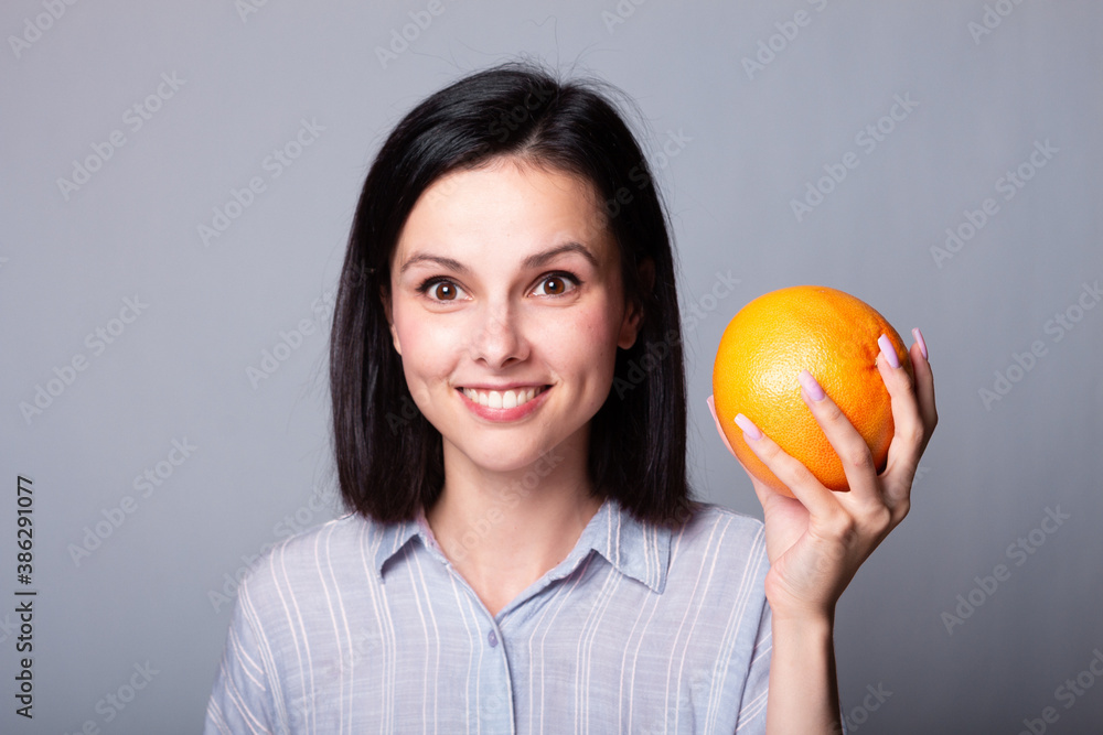 woman in shirt holding grapefruit in her hands woman in shirt holding grapefruit in her hands