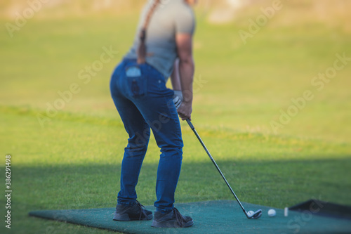 Female golfer girl player practicing and training golf swing on driving range practice, woman playing on golf course, golf ball at golfing complex club resort
