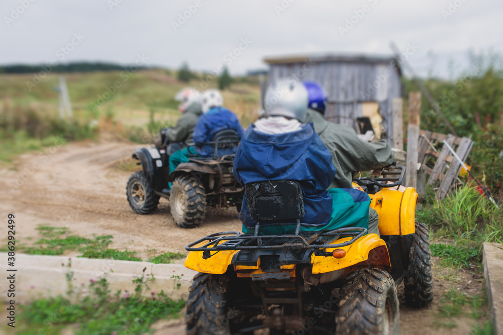 Group of riders riding atv vehicle on off road track, process of driving ATV vehicle, all terrain quad bike vehicle, during offroad competition, crossing a puddle of mud Group of riders riding atv vehicle on off road track, process of driving ATV vehicle, all terrain quad bike vehicle, during offroad competition, crossing a puddle of mud
