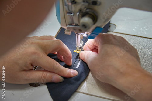 Employee's hands working with his sewing machine in clothing factory