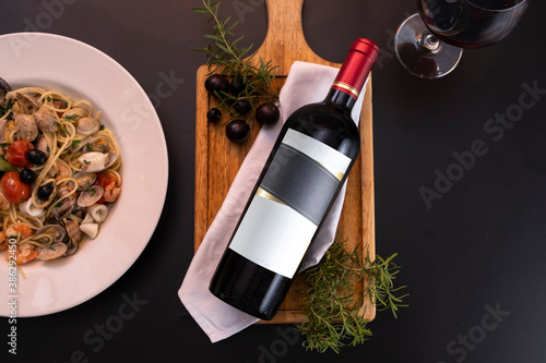 Bottle of wine lying down in black background with some food as decoration photo