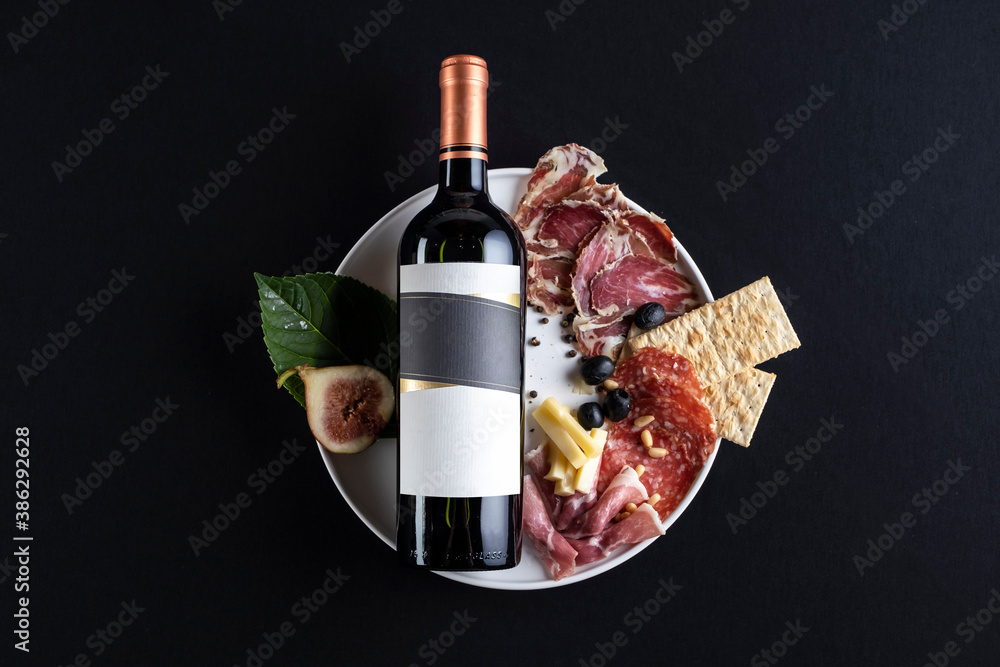 Bottle of wine lying down in black background with some food as