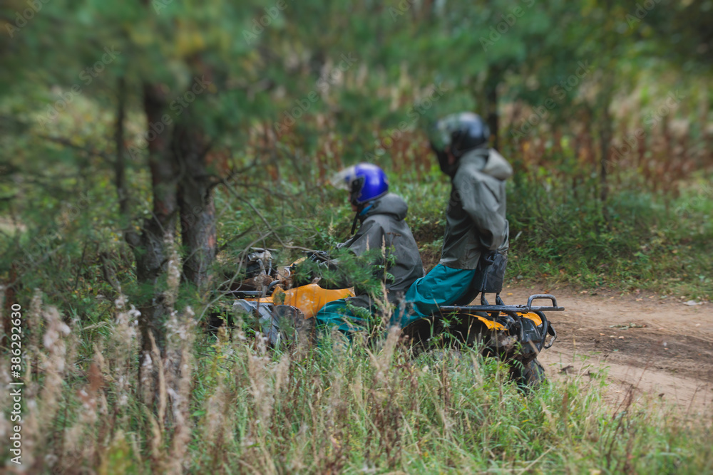 Group of riders riding atv vehicle on off road track, process of driving ATV vehicle, all terrain quad bike vehicle, during offroad competition, crossing a puddle of mud Group of riders riding atv vehicle on off road track, process of driving ATV vehicle, all terrain quad bike vehicle, during offroad competition, crossing a puddle of mud