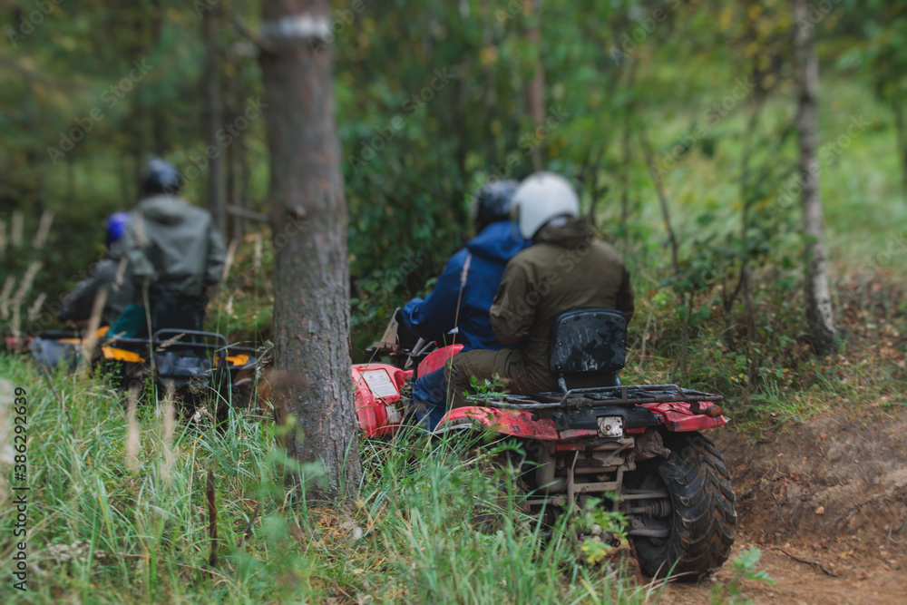 Group of riders riding atv vehicle on off road track, process of driving ATV vehicle, all terrain quad bike vehicle, during offroad competition, crossing a puddle of mud Group of riders riding atv vehicle on off road track, process of driving ATV vehicle, all terrain quad bike vehicle, during offroad competition, crossing a puddle of mud