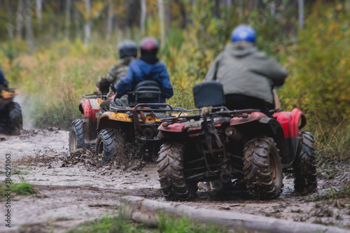 Group of riders riding atv vehicle on off road track, process of driving ATV vehicle, all terrain quad bike vehicle, during offroad competition, crossing a puddle of mud