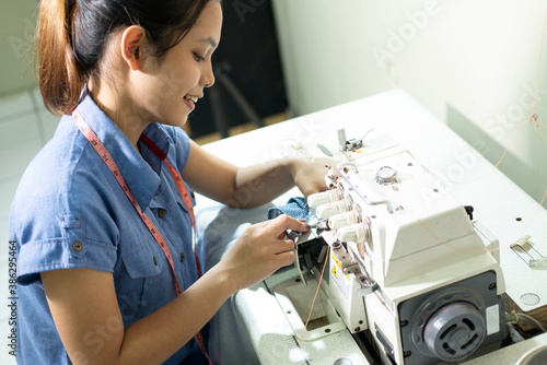 Asian female tailor employee sew using an embroidery machine at a garment factory